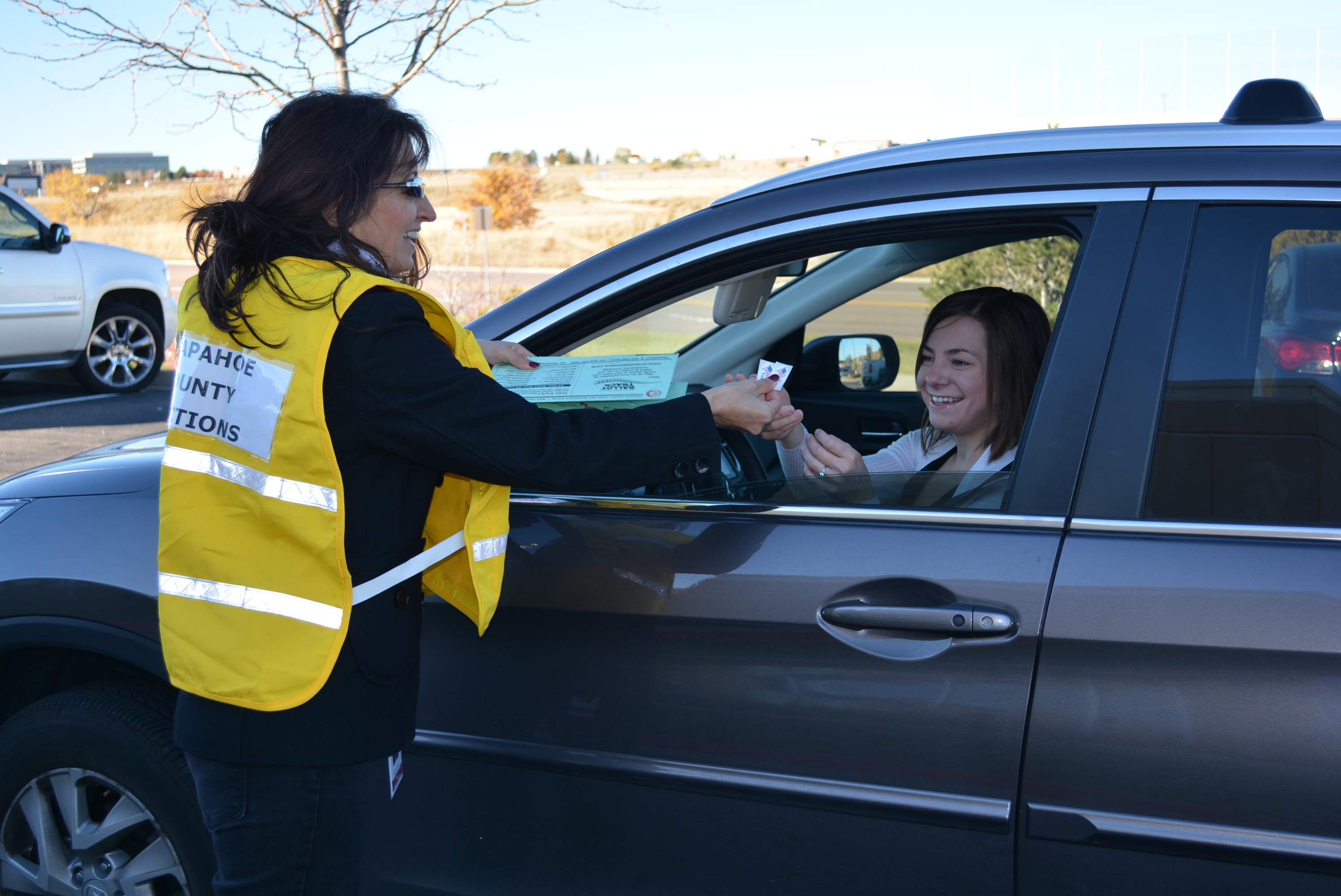 Voter in car delivers ballot to election worker at drive-up drop-off location