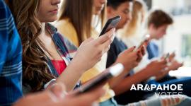 Teenagers look at smartphones, Arapahoe Votes logo