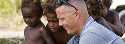 Three children of Solomon Islands stand next to U.S. male citizen